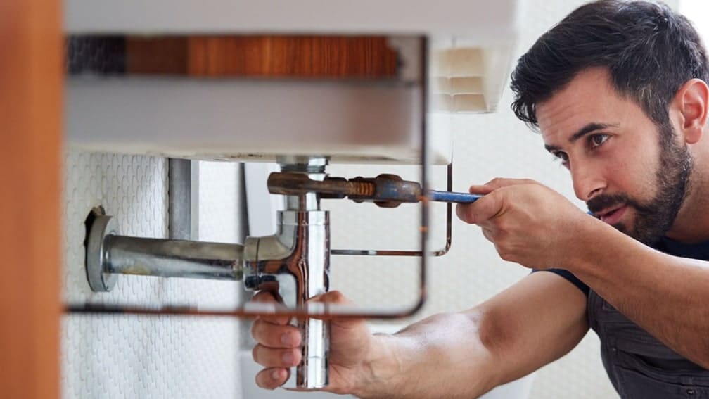 homeowner fixing a leak under a sink